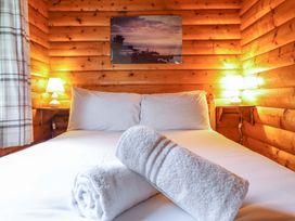 A bedroom with a bed and towels at Y Bwthyn Pren, Cabin 209, Trawsfynydd