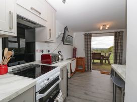 A kitchen area with stove toaster kettle and utensils with a view of outdoor seating at Twilight in Raglan