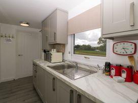 A kitchen with a marble countertop, sink, microwave, wall clock, and window showing an outdoor view at Twilight in Raglan
