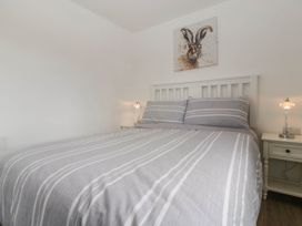 A bedroom with a bed with striped bedding two bedside tables with lamps and a hare painting above the bed at Twilight in Raglan