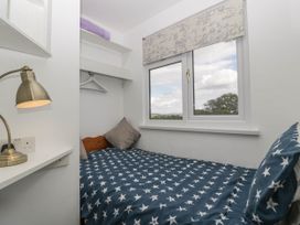 A small bedroom with a bed covered in star patterned bedding a window with a world map blind and a desk lamp at Twilight in Raglan