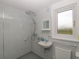 A bathroom with a walk in shower sink mirror and window at Twilight in Raglan