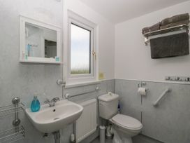 A bathroom with a sink toilet mirror shelf towels and a window at Twilight in Raglan