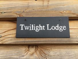A black sign with white text reading Twilight Lodge attached to wooden planks at Twilight in Raglan