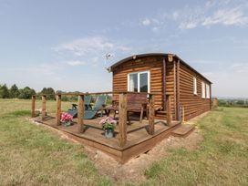 A log cabin with a deck and chairs at Twilight in Raglan