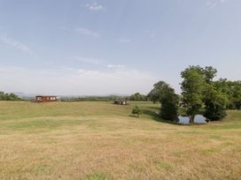 A landscape with wooden cabins, a pond, and trees at Twilight in Raglan