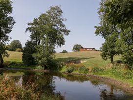 A landscape with a pond and a house on a hill at Twilight in Raglan