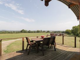 An outdoor seating area with a table and chairs overlooking fields at Twilight in Raglan