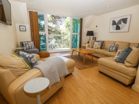 A living room with beige sofas a wooden coffee table and a glass door leading to a balcony at 6 Red Sails in Sandbanks