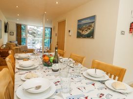 A dining table set with plates glasses and bread in a room with chairs and a living area at 6 Red Sails in Sandbanks