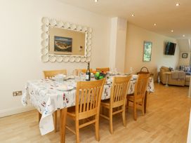 A dining area with a table set with plates glasses and a fruit bowl and wooden chairs at 6 Red Sails in Sandbanks