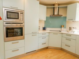 A kitchen with built in microwave oven and oven white cabinets and blue glass backsplash at 6 Red Sails in Sandbanks