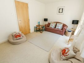 A living room with a sofa cushions with fish patterns small table and chairs and cushions with crab patterns at 6 Red Sails in Sandbanks