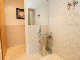 A bathroom with a glass sink pedestal a large mirror tiled walls and a shower area at 6 Red Sails in Sandbanks