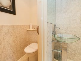 A small bathroom with a toilet and a glass sink at 6 Red Sails in Sandbanks