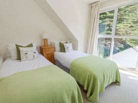 A bedroom with two single beds green blankets and a wooden nightstand with a lamp near a window at 6 Red Sails in Sandbanks