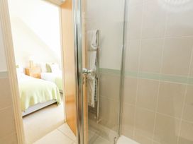 A bathroom with a glass shower screen and a towel rack next to a bedroom with two beds and a bedside table at 6 Red Sails in Sandbanks