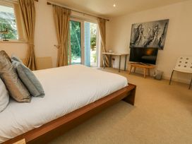 A bedroom with a bed cushions television on table and glass doors with curtains at 6 Red Sails in Sandbanks