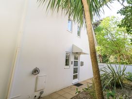 The exterior side of a white building with a door and windows surrounded by a tiled pathway and green plants at 6 Red Sails in Sandbanks