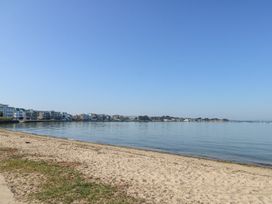 A sandy beach with calm water and buildings along the shoreline at 6 Red Sails in Sandbanks