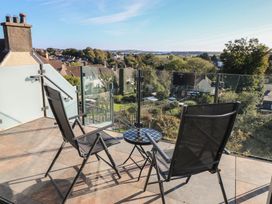 A balcony with chairs and a table overlooking a view at 10 Brython Place Tenby