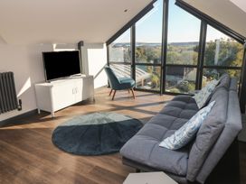A living room with a sofa, armchair, and TV at 10 Brython Place Tenby
