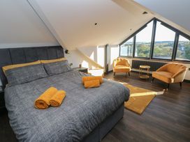 A bedroom with a bed and chairs at 10 Brython Place in Tenby