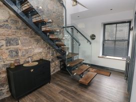 A staircase with a glass railing and wooden treads in a hallway at 10 Brython Place in Tackley