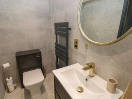 A bathroom with a toilet, hand basin, mirror, towel rack, and toilet paper holder at 10 Brython Place Tackley
