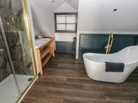 A bathroom with a shower, bathtub, sink, and storage cabinet at 10 Brython Place Tackley