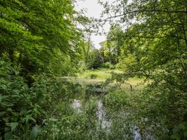 A pond surrounded by greenery at Keepers Cottage in Devizes