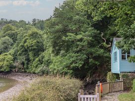 A house next to a river with trees at The Boat House in Ashprington