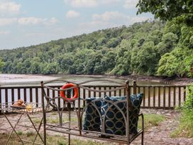 An outdoor seating area with a bench and view of the river at The Boat House in Ashprington