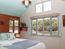 A bedroom with a bed and windows at The Boat House in Ashprington