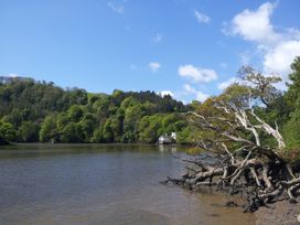 A river with trees and a house in the background at The Boat House in Ashprington