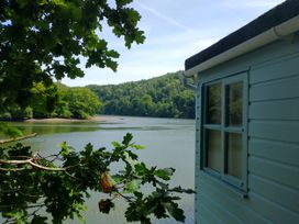 A view of water and trees from the side of a building at The Sharpham Boat House in Ashprington