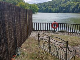 A view of a lake with a metal bench and a life buoy at The Sharpham Boat House in Ashprington