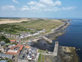 An aerial view of a coastal area with houses and a pier at Puffin Cottage Craster