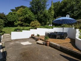 A garden with a patio and an umbrella at Happiness Cottage in Piddlehinton