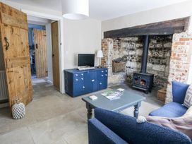 A living room with a wood stove and television at Happiness Cottage Piddlehinton
