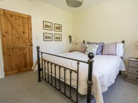 A bedroom with a bed and wooden door at Happiness Cottage Piddlehinton