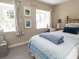 A bedroom with a bed and windows at Happiness Cottage in Piddlehinton