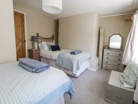 A bedroom with two beds and a chest of drawers at Happiness Cottage in Piddlehinton