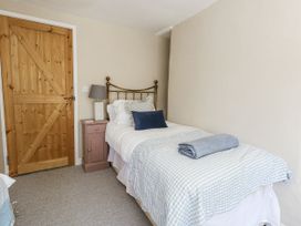 A bedroom with a single bed and wooden door at Happiness Cottage in Piddlehinton