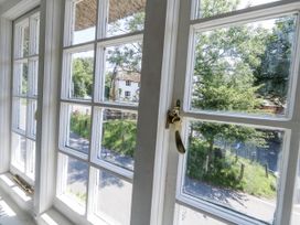A window showing a view of a road and trees at Happiness Cottage in Piddlehinton