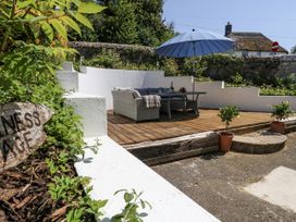 A garden area with sofa, table, umbrella, and potted plants at Happiness Cottage in Piddlehinton