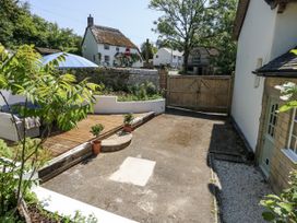 A garden with decking and potted plants at Happiness Cottage in Piddlehinton