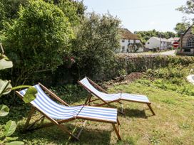 A garden with deck chairs and greenery at Happiness Cottage in Piddlehinton