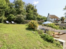 A garden with loungers and a flower bush at Happiness Cottage Piddlehinton