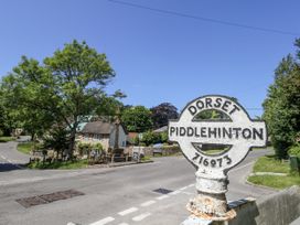 A view of a signpost in Piddlehinton with houses and trees in the background at Happiness Cottage Piddlehinton